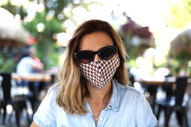 Restoranda pamuk maskeli genç bir kadın gezgin. Koronavirüsü önlemek için önlemler.