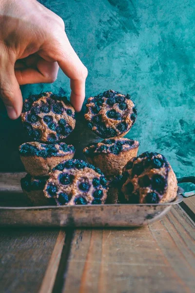 Vértes egy férfi ujjai elhelyezés egy finom áfonyás Muffin egy halom teasütemények — Stock Fotó