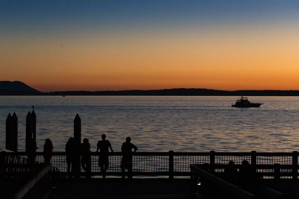 Οι άνθρωποι απολαμβάνουν το ηλιοβασίλεμα στην προβλήτα της θάλασσας — Φωτογραφία Αρχείου