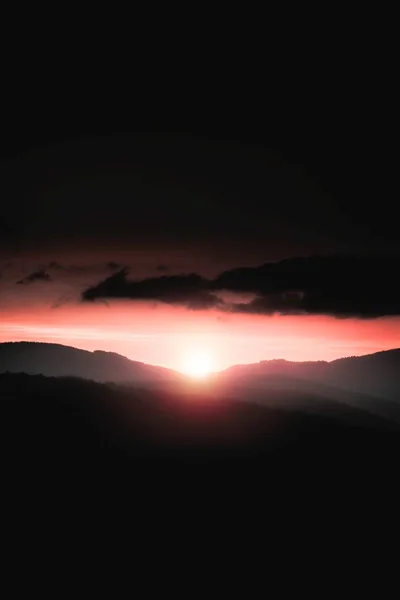 Hermosa luz del sol sobre las colinas en el horizonte con un cielo nublado oscuro —  Fotos de Stock