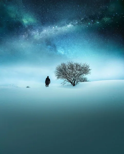 Fantazie koncept cestovatel oblečený v černé objevování ve sněhu s dechberoucí hvězdnou oblohou — Stock fotografie