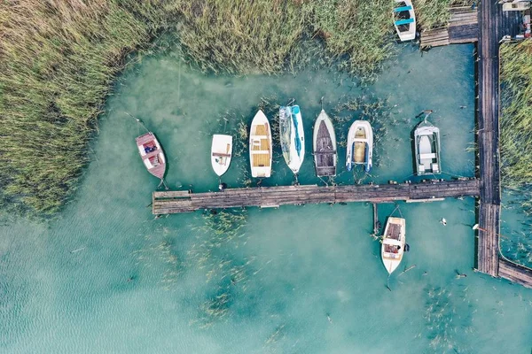 An overhead shot of a little dock at the coast with parked fishing boats