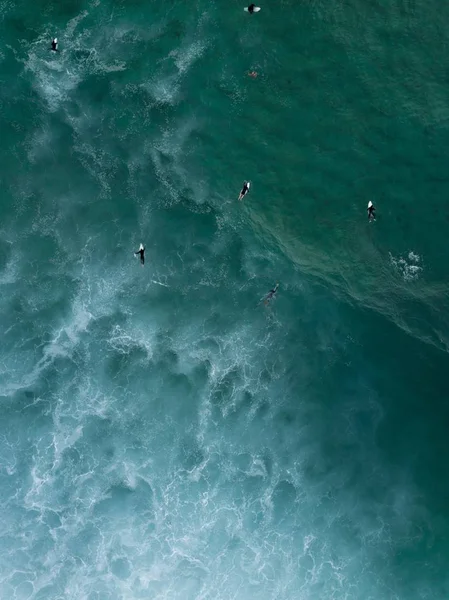 Aerial shot of surfers swimming laying on their boards in the sea waiting for strong waves to come — ストック写真