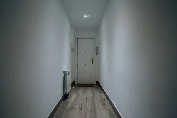Longo tiro de uma porta e radiador em um corredor com paredes brancas — Fotografia de Stock
