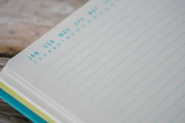 Livro didático azul aberto com marcadores de data no topo em uma superfície de madeira — Fotografia de Stock