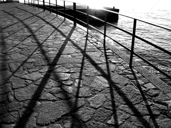 Grayscale tiro de uma ponte de pedra com um corrimão pelo corpo de água — Fotografia de Stock