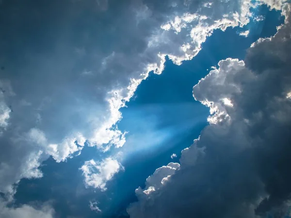 Plan à angle bas d'un ciel avec nuages et lumière du soleil qui brille à travers le milieu — Photo