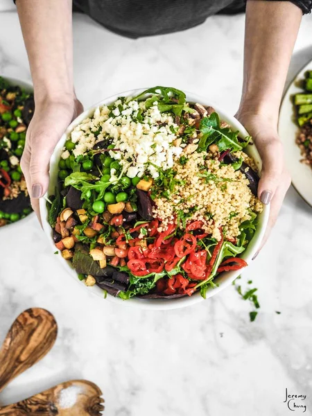 High angle shot of a salad with vegetable leaf, tomatoes, cheese and nuts in a round plate — Stock Photo, Image