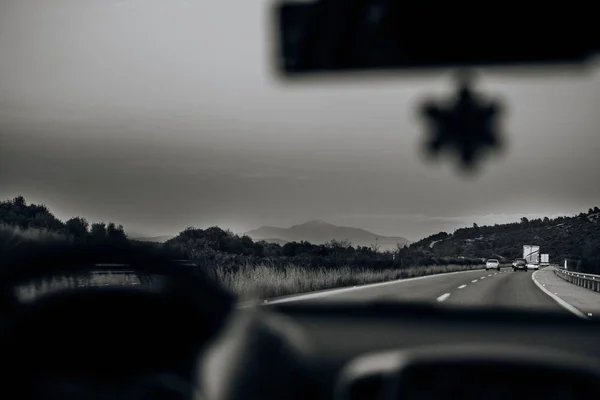 Black and white shot of a drive-through road taken from inside of a car — Stock Photo, Image