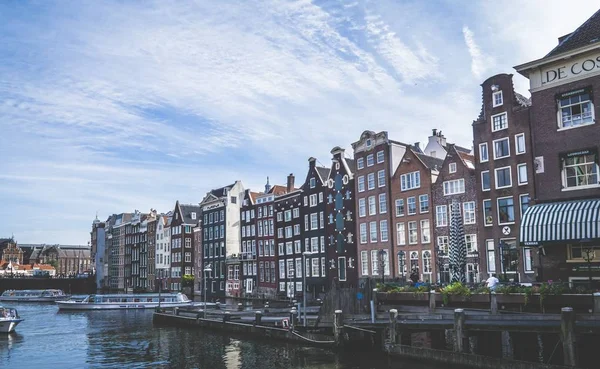 Amplio plano de edificio alto junto al otro cerca del agua con barcos en Amsterdam —  Fotos de Stock