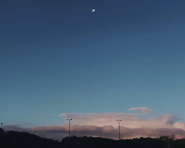 Largo tiro de meia lua no céu sobre as nuvens cinzas — Fotografia de Stock