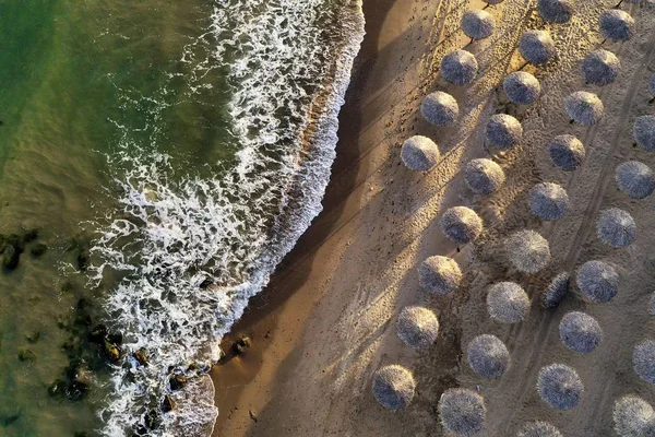 Overhead tiro de belas ondas de praia atingindo a costa com guarda-sóis de praia em um dia ensolarado — Fotografia de Stock