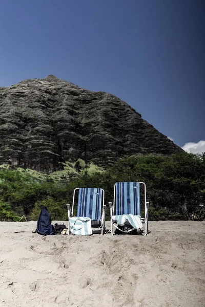 Due panchine su una spiaggia con una piccola collina sullo sfondo — Foto Stock