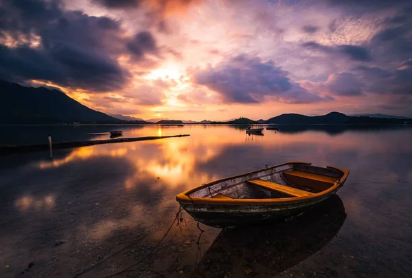 Schöne Aufnahme eines kleinen Sees mit einem hölzernen Ruderboot im Fokus und erstaunlichen Wolken am Himmel — Stockfoto