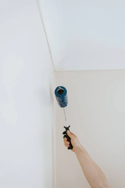 Κάθετο πλάνο ενός ατόμου που ζωγραφίζει λευκούς τοίχους με μπλε χρώμα με βούρτσα από κύλινδρο βαφής — Φωτογραφία Αρχείου