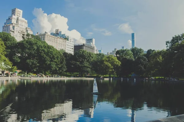 Ein spiegelnder See in einem Park mit hohen Gebäuden und schönem Himmel — Stockfoto