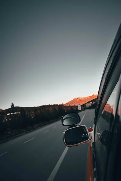 Vertikale Aufnahme der linken Außenspiegel eines fahrenden Autos mit Reflexionen — Stockfoto