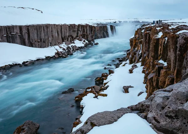 Belo tiro de um rio em uma superfície rochosa nevada — Fotografia de Stock