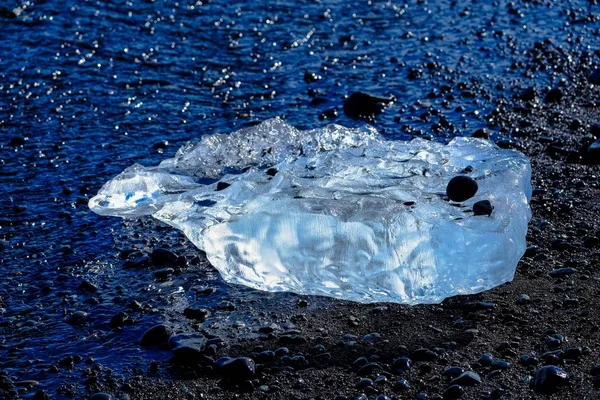Nahaufnahme einer Eisscherbe am Ufer mit winzigen Felsen — Stockfoto