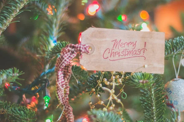 Primer plano de una decoración de árbol de Navidad con la escritura "Feliz Navidad" en él —  Fotos de Stock