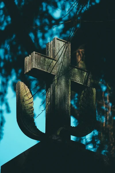 Tiro vertical de uma cruz de pedra com fundo borrado — Fotografia de Stock