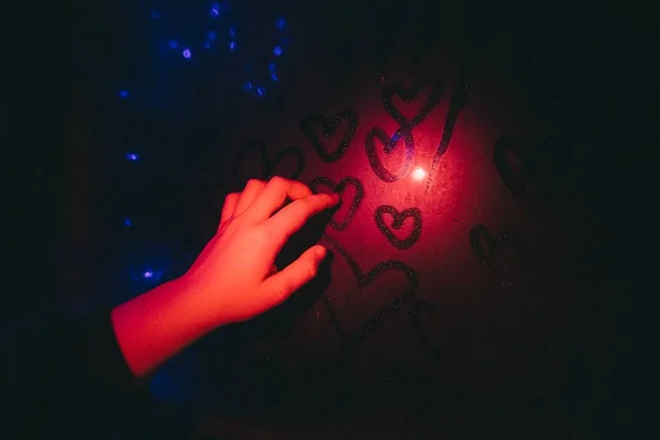 Mladá ženská kreslila srdce v okně s prstem v pokoji — Stock fotografie