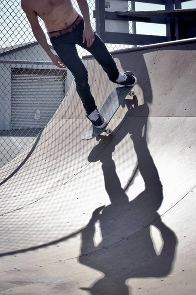 Fit male riding a skateboard on a slope at a skatepark