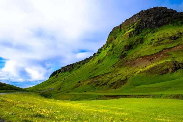 Γρασίδι κοντά σε ένα καταπράσινο βουνό κάτω από συννεφιασμένο ουρανό — Φωτογραφία Αρχείου