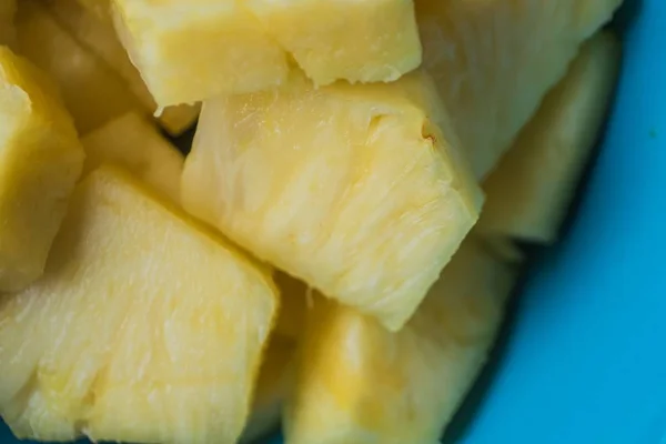 Primer plano de piezas de piña cortadas en un tazón azul sobre un fondo de madera —  Fotos de Stock