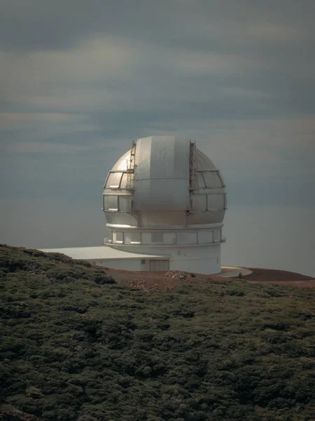 Vertical shot of an observatory building on a mountain near a grassy field — Stock Photo, Image