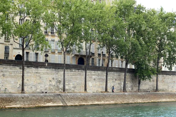 Wide shot of a beautiful canal and a stone fence with trees with a loving couple kissing each other — Stock Photo, Image