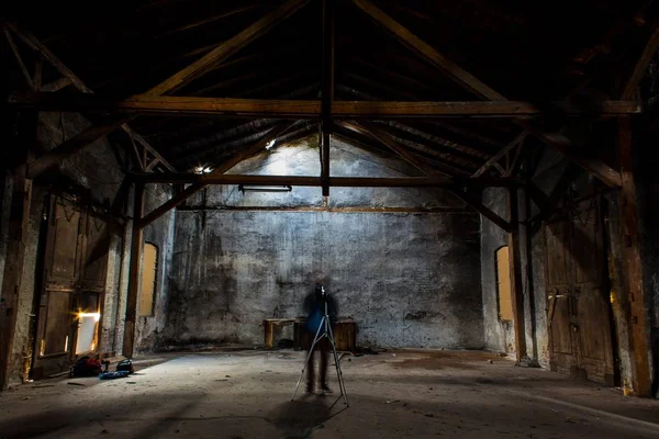 Silhuett av en fotograf med ett stativ i ett stort tomt rum — Stockfoto