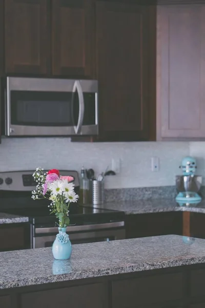 Красивый снимок цветов в керамической вазе на кухонном столе — стоковое фото