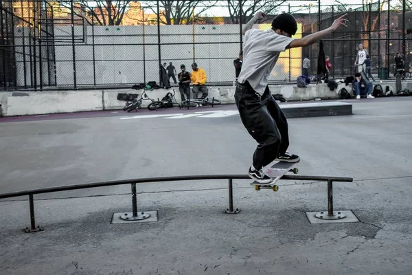 Скейтбордист делает трюки, балансируя на металлической трубе в скейт-парке — стоковое фото