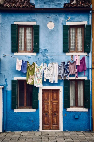 Beautiful vertical symmetric shot of a suburban blue building with clothes hanging on a rope — 스톡 사진