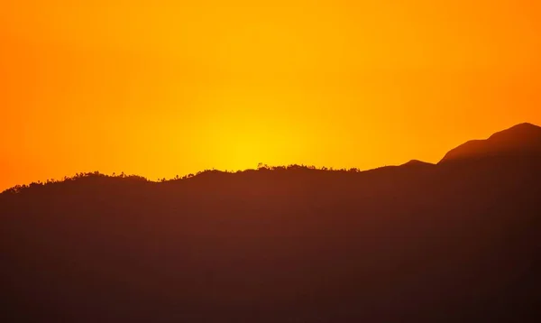 Silhueta de uma montanha com um céu laranja no fundo — Fotografia de Stock