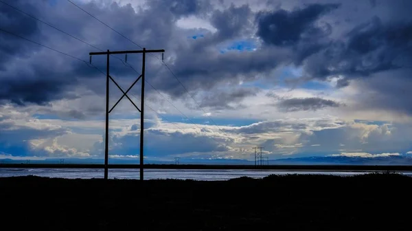 Silhouette eines grasbewachsenen Feldes mit Sendemast über dem Meer unter wolkenverhangenem Himmel — Stockfoto