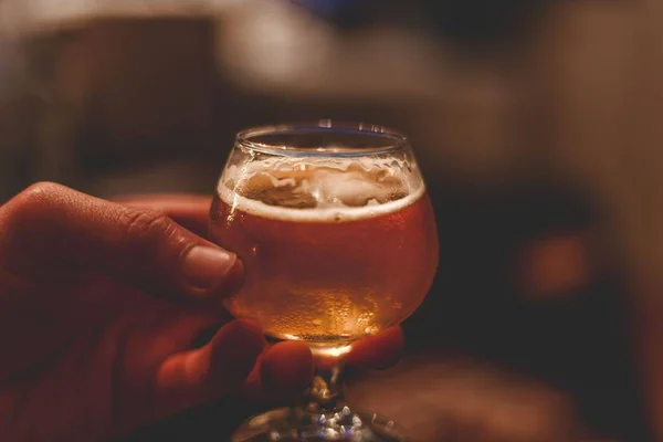 Closeup shot of a snifter beer glass filled with beer to the brim — Stock Photo, Image
