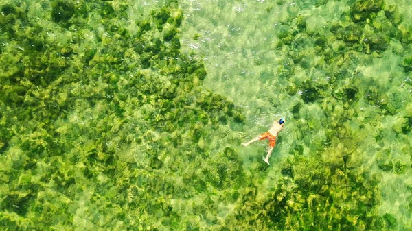 Aérea sobrecarga tiro de masculino natação na água com bonito verde recifes de coral embaixo — Fotografia de Stock