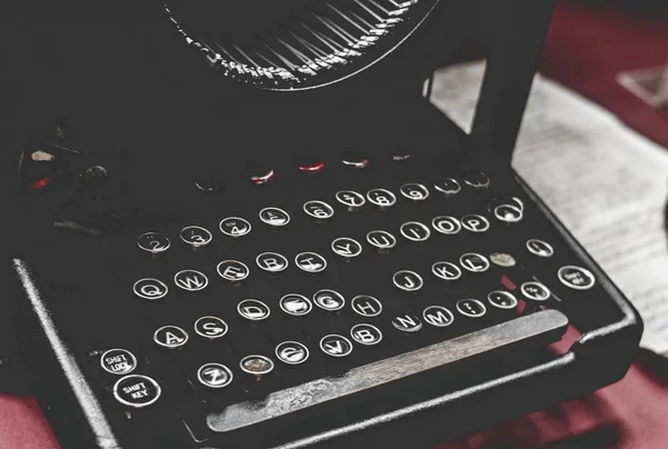 Closeup shot of an old vintage typewriter on a red desk with paper on the side — Stock Photo, Image