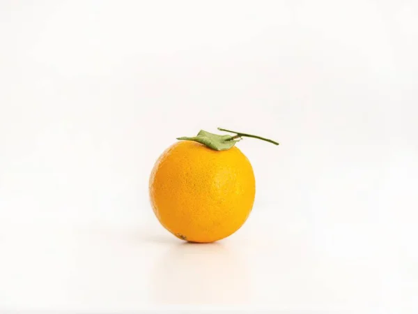一个孤立的整个橙色的特写，在明亮的浅粉色背景上有一片叶子 — 图库照片