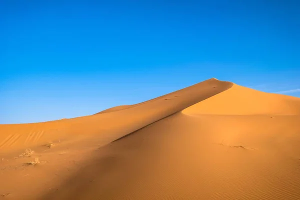 Mooie foto van een zandduin met een heldere blauwe hemel op de achtergrond — Stockfoto