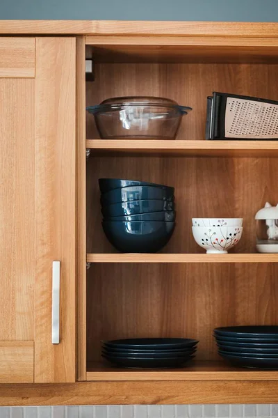 Vertical shot of dishware in a wooden crockery cabinet — Stock Photo, Image