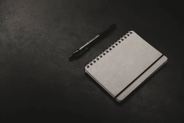 Un bloc de notas con una pluma sobre un fondo oscuro — Foto de Stock