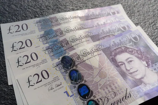 Closeup shot of four twenty-pound sterling bills on a gray background — Stock Photo, Image