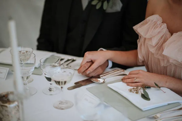 Closeup tiro de um casal de mãos dadas em uma mesa de casamento — Fotografia de Stock
