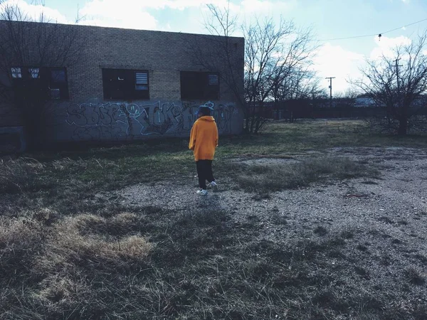 Niebieskowłosy dziewczyna idzie w pobliżu starego opuszczonego budynku z graffiti na ścianach — Zdjęcie stockowe