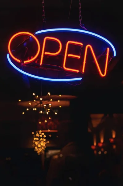 Foto vertical de un cartel de neón naranja y azul que dice "ABIERTO" en un bar — Foto de Stock