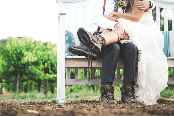 Pareja cariñosa abrazándose unos a otros sentados en un banco blanco con un fondo natural borroso — Foto de Stock