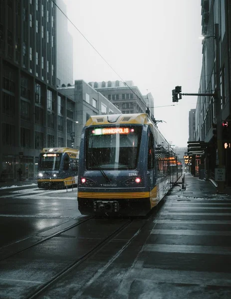 Vertikal bild av ett gult och grått passagerartåg mitt på gatan — Stockfoto